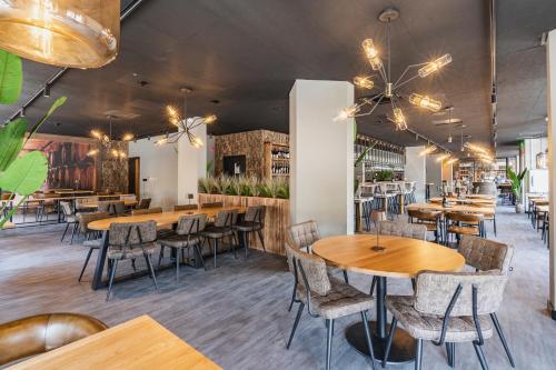 una sala da pranzo con tavoli e sedie in legno di Dormio Wijnhotel Valkenburg a Valkenburg