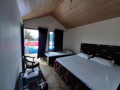 a bedroom with a bed and a chair and a window at Lake Haven Resort, Sari, Chopta in Sari