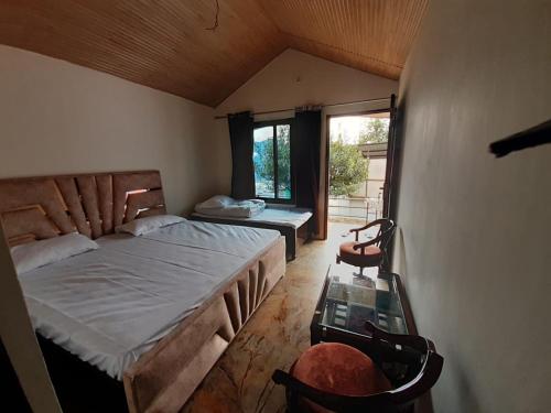 een slaapkamer met een bed, een tafel en een raam bij Lake Haven Resort, Sari, Chopta in Sari