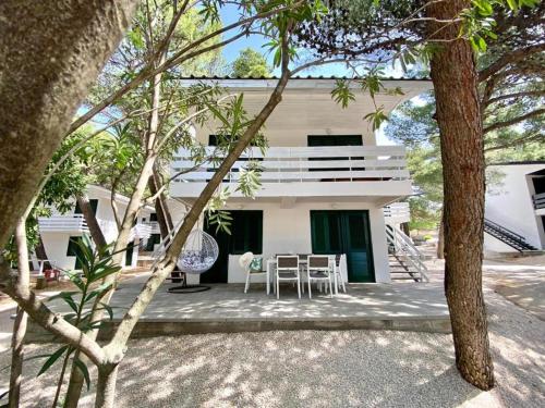 a white house with a table and chairs in front of it at Family Resort Urania in Baška Voda