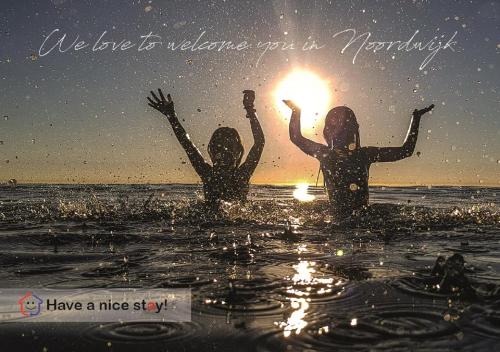 dos chicas en el agua con el sol en sus manos en Guesthouse Salty Life near the beach en Noordwijk aan Zee