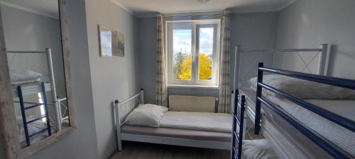 a small room with two bunk beds and a window at Hostel Centrum-Kamienica 1924 in Szczecinek