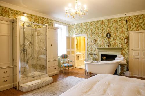 a bathroom with a tub and a shower and a fireplace at Gileston Manor Luxury B&B in Barry