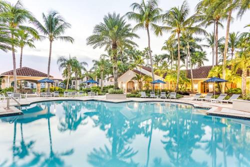 einen Pool in einem Resort mit Palmen in der Unterkunft Stunning & Spacious Apartments at Miramar Lakes in South Florida in Miramar