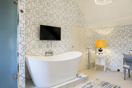 a bathroom with a tub and a tv on a wall at Gileston Manor Luxury B&B in Barry