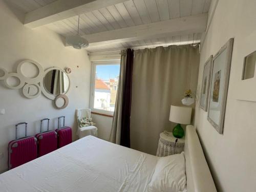 um quarto com uma cama branca e uma janela em Le Muse casa vacanze em Scoglitti