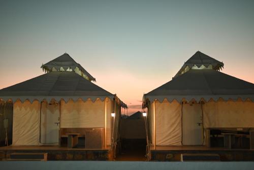 two yurt buildings with the sunset in the background at NK Desert Camp Jaisalmer in Sām