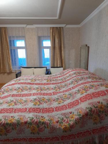 a bedroom with a large bed with a colorful quilt at Dusheti Baga in Dushetʼi