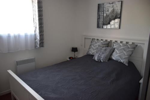 a bedroom with a large bed with gray sheets and pillows at location maison à Cajarc 46160 (Lot) in Cajarc