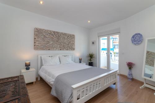 a bedroom with a large white bed and a window at Casa Angelica in Praia do Carvoeiro