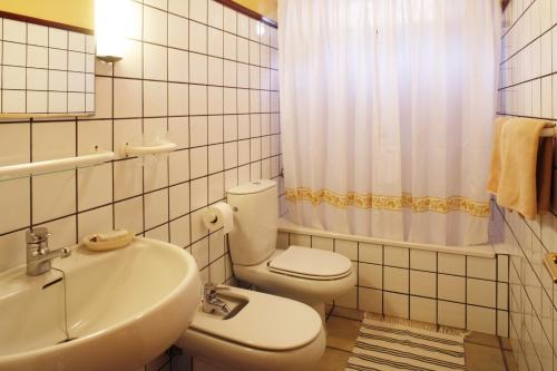 a white bathroom with a toilet and a sink at Casa rural en el Risco de Agaete A in Agaete