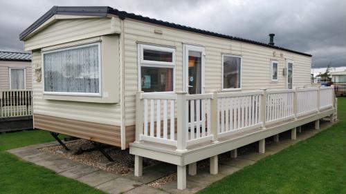 a mobile home with a porch and a deck at 6 Berth heated on The Chase (Albany II) in Skegness
