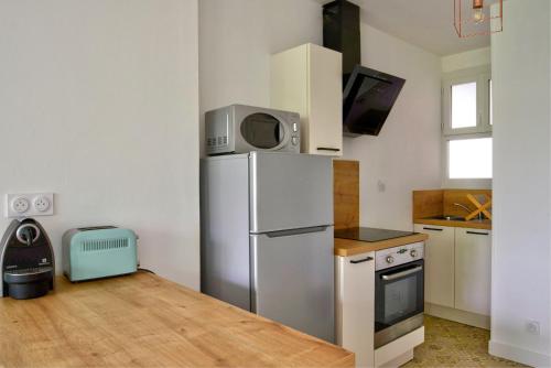 une cuisine avec un réfrigérateur et un micro-ondes dans l'établissement Charmant T2 lumineux ► Centre-Ville ► Tout équipé, à Saumur