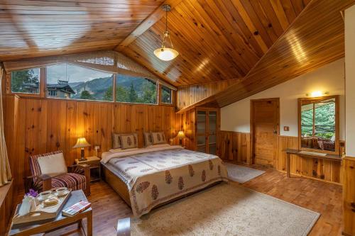 een slaapkamer met een bed in een kamer met houten wanden bij StayVista at Himalayan Retreat in Manāli