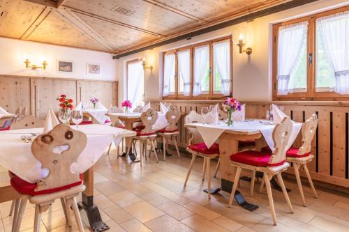 un comedor con mesas, sillas y ventanas en Hotel Landgasthof Staila, en Fuldera