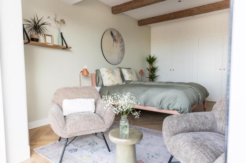 een slaapkamer met een bed en 2 stoelen bij de Zuiderstolp in Zuidermeer