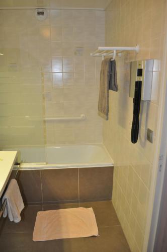 a bathroom with a shower with a tub and a sink at Logis Hotel au tambour in Reims