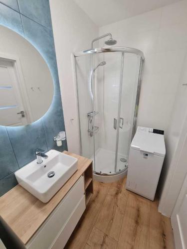 uma casa de banho com um chuveiro e um lavatório branco em Apartament CARO em Mrzeżyno