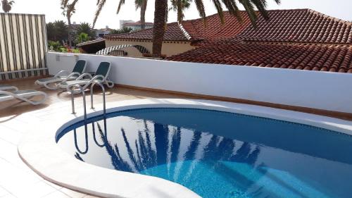 a swimming pool with chairs next to a house at La Quinta Villas in San Miguel de Abona