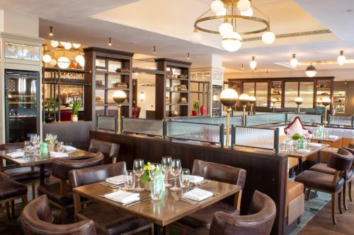 a restaurant with tables and chairs and a bar at Clayton Hotel Cambridge in Cambridge