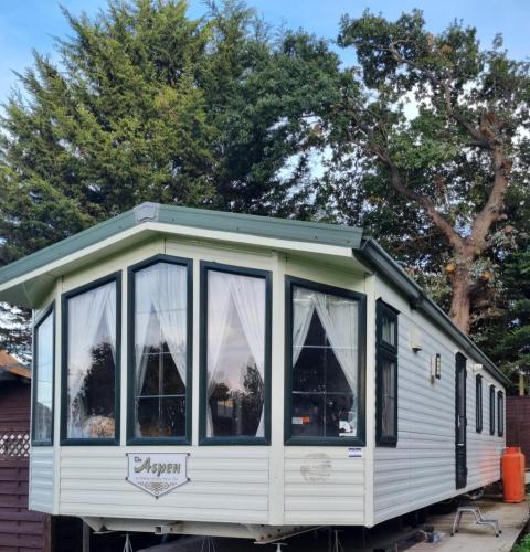 una pequeña casa sentada en un remolque con árboles en el fondo en Quite 3 Bedroom Static Caravan en Sidcup