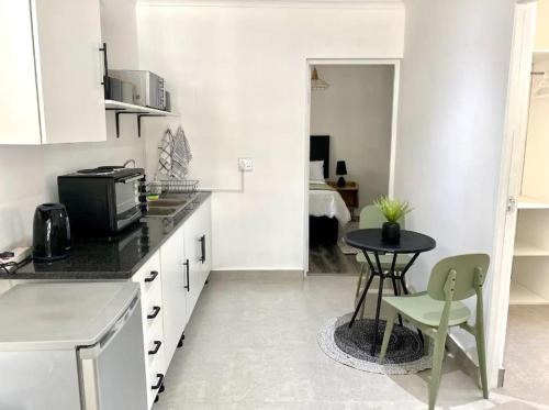 a kitchen with a small table and a room with a bed at Angazi Guesthouse Unit 3 - Modern 2 Bedroom Apartment with Pool in Hillcrest