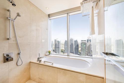 a bathroom with a tub and a large window at Address Dubai Marina - 1B Apt, Full Marina View with 5 Star Hotel Facilities by Gardenia Suites in Dubai