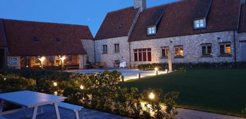 a building with a yard with a table and lights at vakantiehoeve 't Goed ter Leeuwen in De Haan