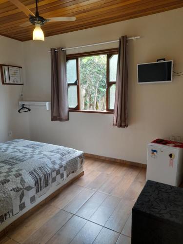 ein Schlafzimmer mit einem Bett und einem Fernseher an der Wand in der Unterkunft Le Marchand de Sable- Suites e apartamento in Búzios