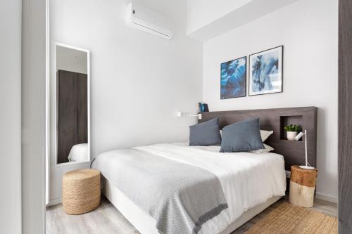 um quarto branco com uma cama grande e almofadas azuis em Studios Terra & Mar em Lisboa