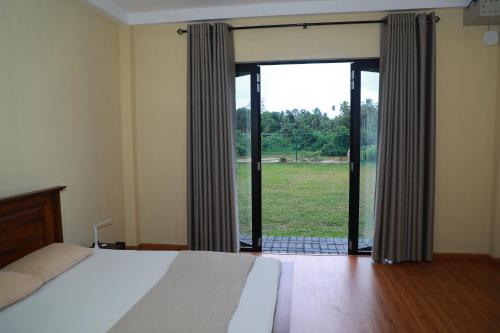 una camera con un letto e una grande finestra di Kosgama Riverside Resort a Kosgama