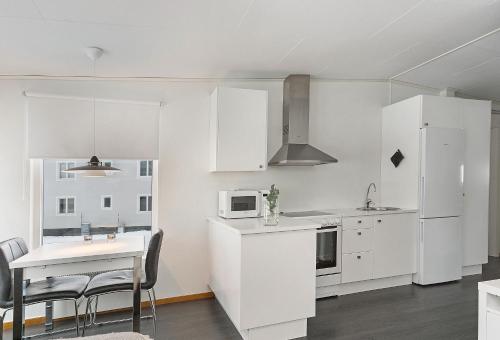 une cuisine avec des placards blancs et une table avec des chaises dans l'établissement Private Chalet with Sauna, à Kiruna