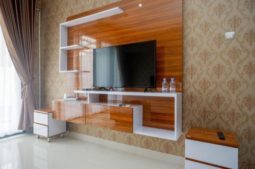 ein Wohnzimmer mit einem Fernseher an der Wand in der Unterkunft The Lavana Greenkhaza Villa Jogja in Yogyakarta