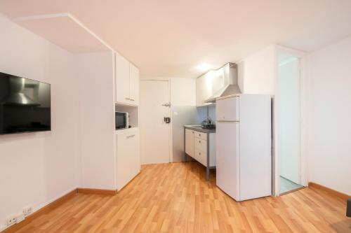  La cuisine est équipée de placards blancs et d'un réfrigérateur. dans l'établissement Homenfun Barcelona Park Güell, à Barcelone