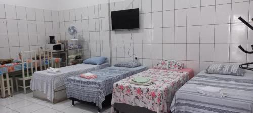 a room with three beds and a tv on the wall at Aluguel de loft mobiliado em Cuiabá in Cuiabá