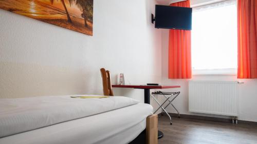 Zimmer mit einem Bett, einem Tisch und einem Fenster in der Unterkunft Aalreuse in Rostock