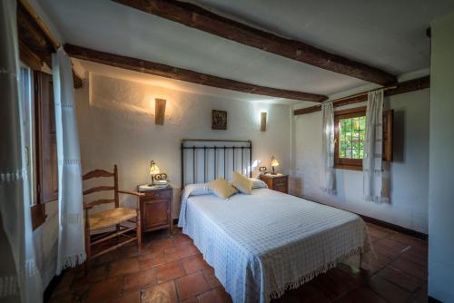 a bedroom with a bed and a chair and windows at Al Agia - Los Molinos de Padul in Padul