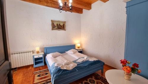 a bedroom with a bed with a blue headboard and two lamps at Hanul Moara cu Noroc in Ineu