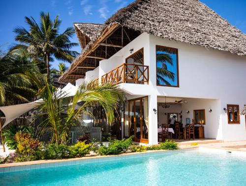 a villa with a swimming pool in front of a house at Alladin Boutique Beach Hotel and SPA Zanzibar in Matemwe
