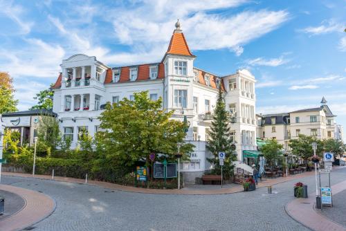 un bâtiment blanc avec un toit orange dans une rue dans l'établissement Hotel Buchenpark, à Bansin