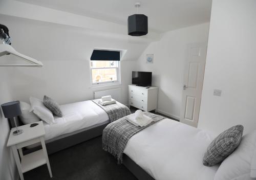 a bedroom with two beds and a window at Exmouth - Apartment 2, Strand House - Modern 2 Bedroom Apartment, Perfect Location For Access To Beach & Town Centre - Sleeps 6 Guests - Hosted By RENTMYHOUSE in Exmouth