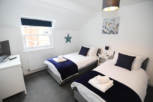 a bedroom with two beds and a desk and a window at Strand House Flat 2 Free Parking, by RentMyHouse in Exmouth