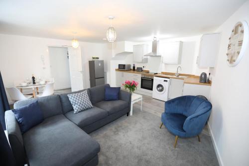 a living room with a blue couch and a kitchen at Strand House, Exmouth, By RentMyHouse in Exmouth