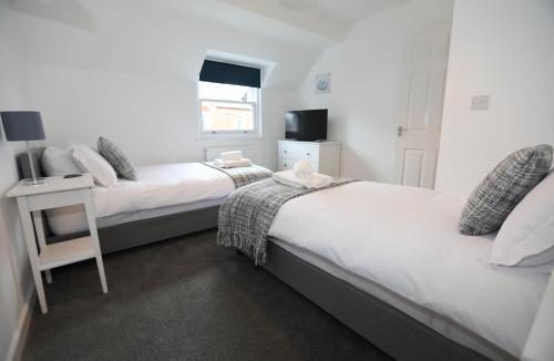 a bedroom with two beds and a table and a television at Exmouth - Apartment 2, Strand House - Modern 2 Bedroom Apartment, Perfect Location For Access To Beach & Town Centre - Sleeps 6 Guests - Hosted By RENTMYHOUSE in Exmouth