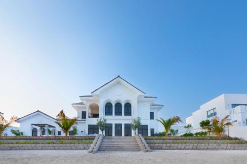 una casa bianca sulla spiaggia con palme di Maison Privee - Luxury Villa with Dramatic View Private Beach & Pool a Dubai