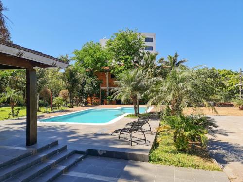 a swimming pool with chairs and trees and a building at Terrazas Vista Verde in Asunción