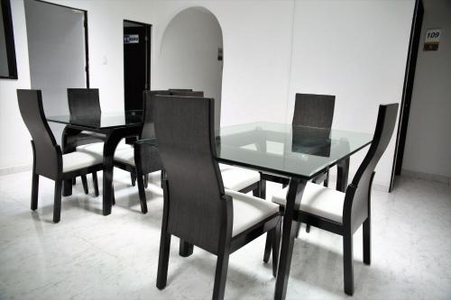 uma sala de jantar com uma mesa de vidro e cadeiras pretas em Hotel Madeira em Manizales