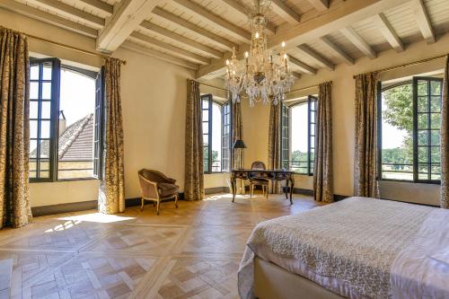 a bedroom with a bed and a dining room with windows at CHATEAU DE LASCOUPS in Saint-Martin-des-Combes