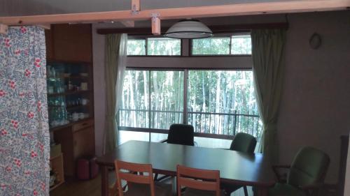 a dining room table with chairs and a large window at Guesthouse Oomiya base 大宮基地別荘 in Chiba