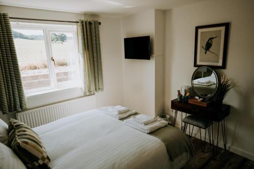 a bedroom with a bed and a mirror and a window at The Lodge by Cefn Tilla in Usk